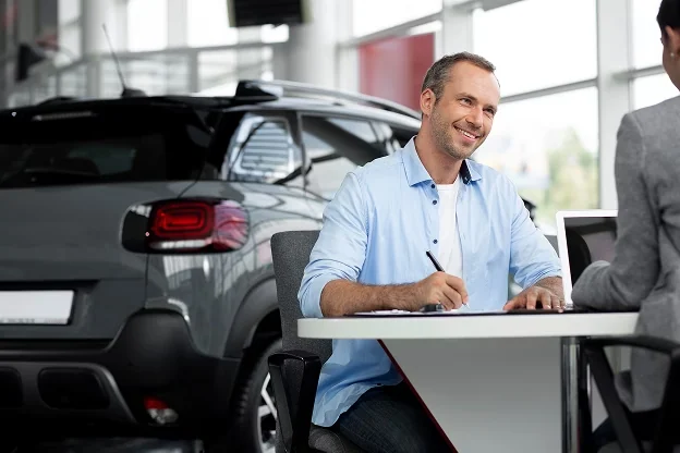 Vendedor de loja de seminovos usando o sistema ao lado de um carro