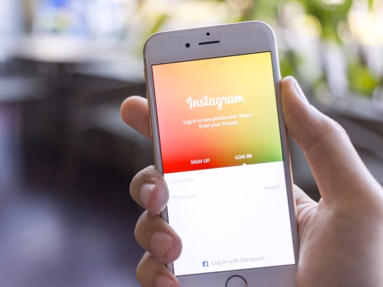 Mãos segurando celular com a tela de entrada do Instagram aberta