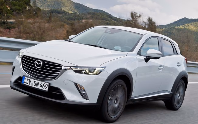 SUV branco da Mazda rodando em estrada com montanhas ao fundo