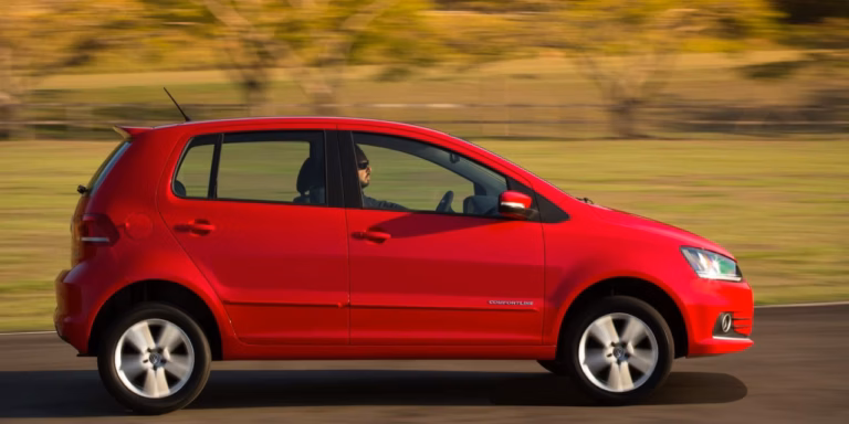 Volkswagen Fox vermelho em movimento numa estrada com fundo desfocado