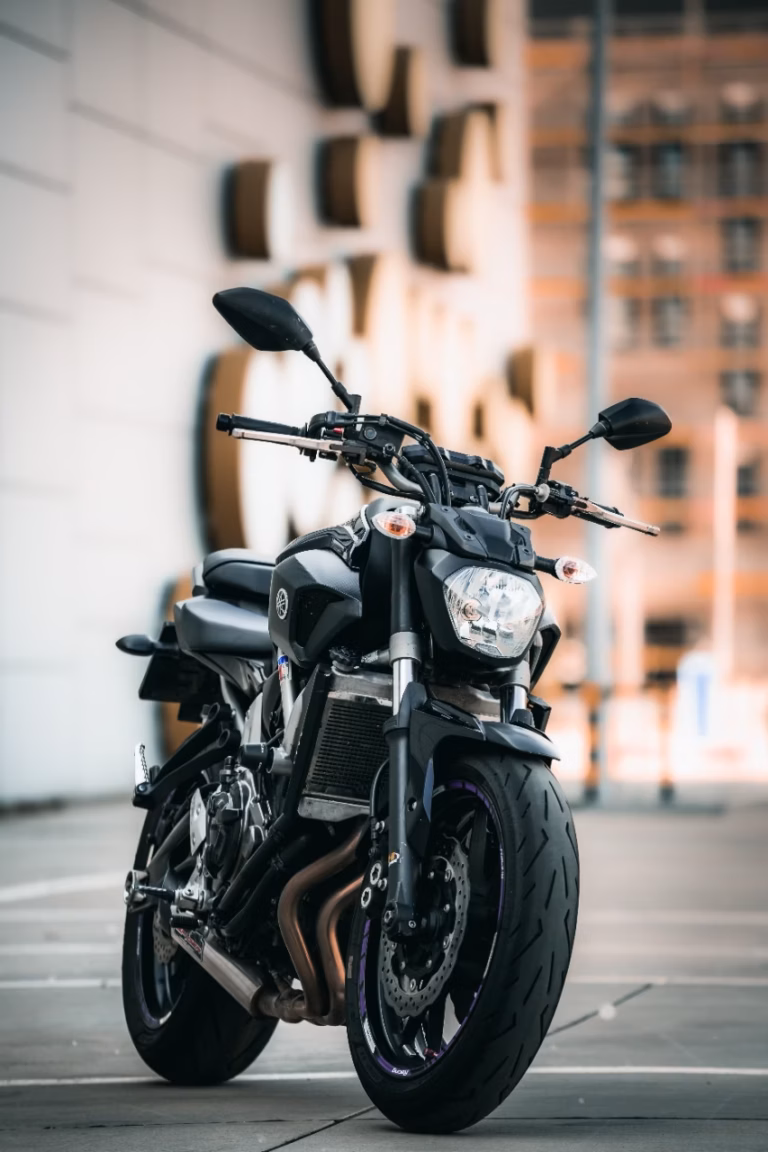 Moto preta estacionada na calçada ao lado de um prédio