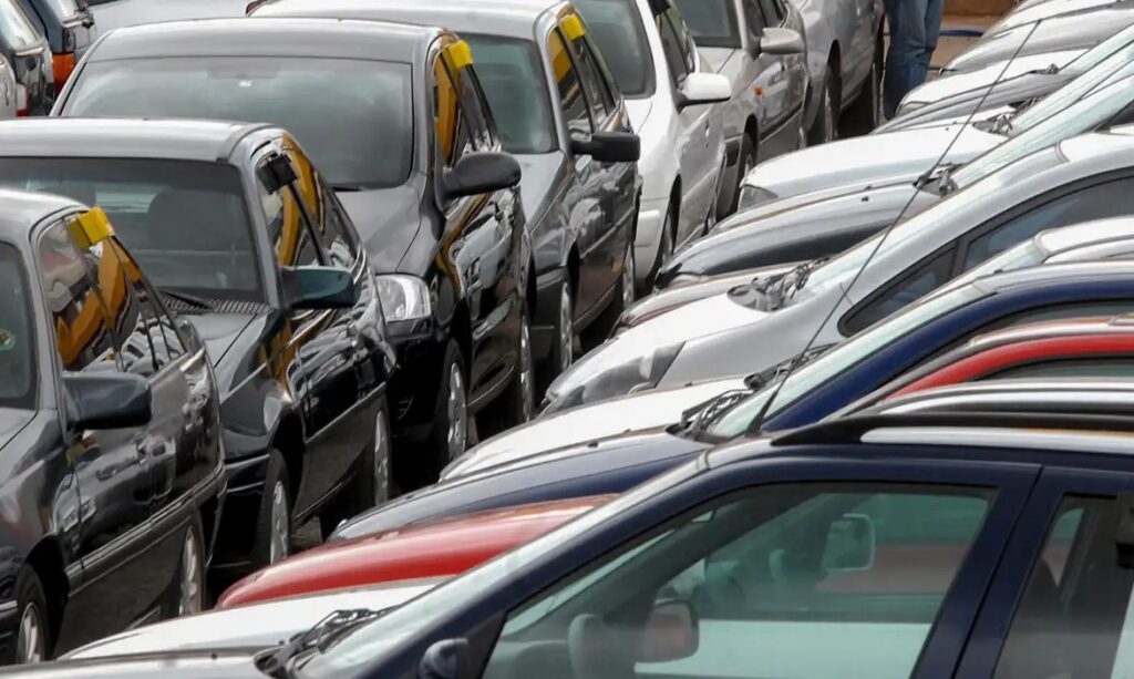 Carros usados estacionados lado a lado em um pátio lotado