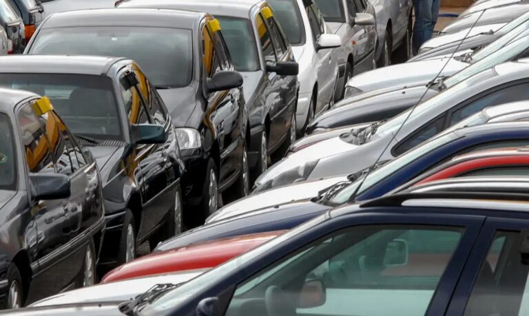 Carros usados estacionados lado a lado em um pátio lotado