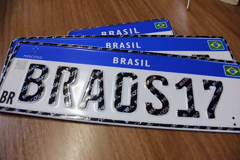 Placas Mercosul empilhadas sobre mesa de madeira, a da frente com BRA0S17