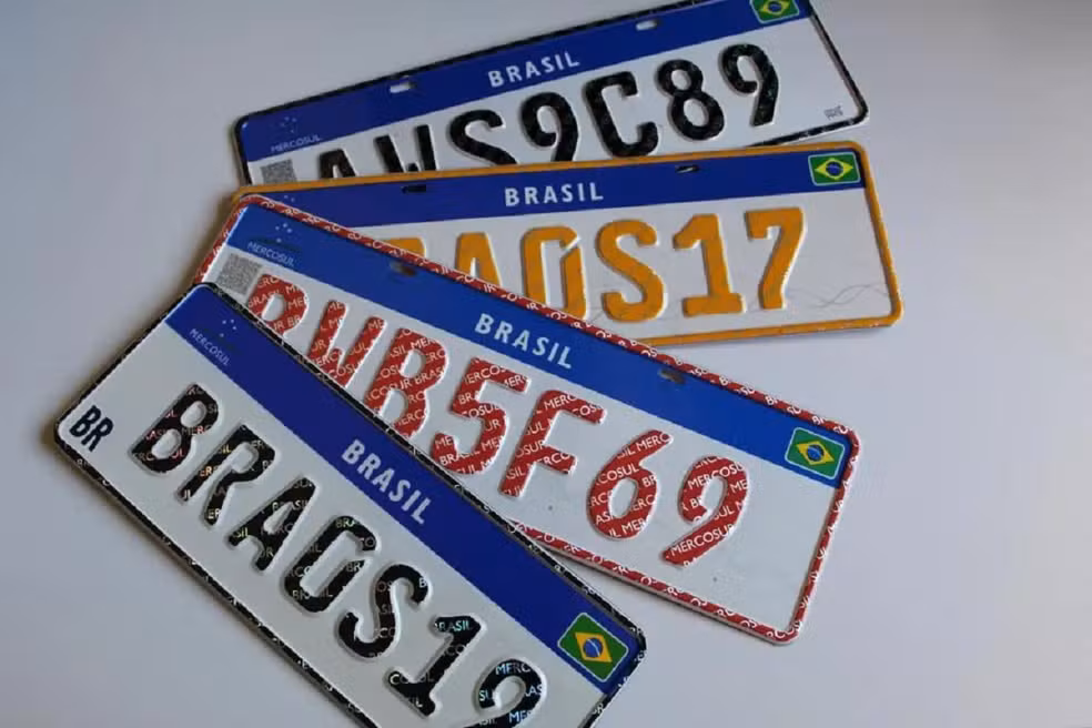 Várias placas Mercosul sobrepostas sobre fundo cinza, como BRA0S19 e BRA5F69