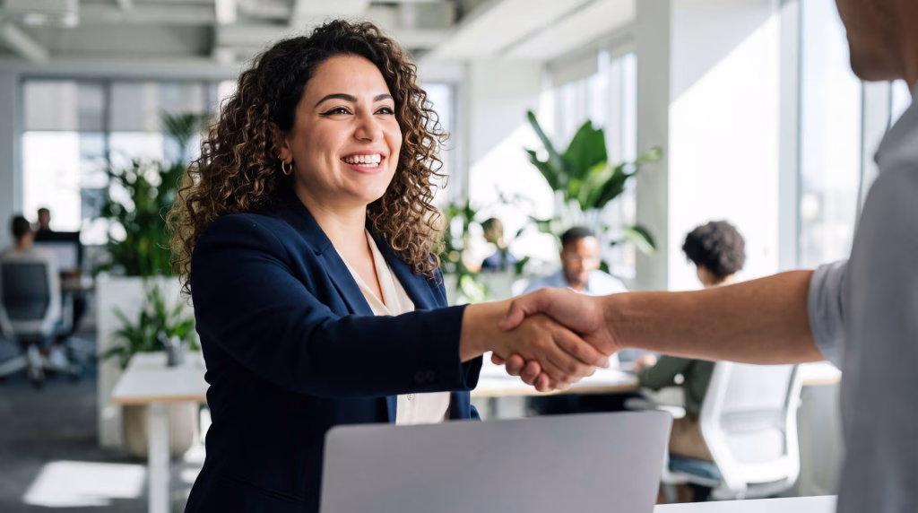 Empresária sorridente apertando a mão de alguém no escritório
