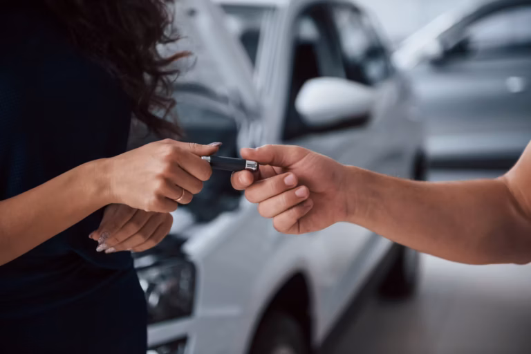 Mulher recebendo a chave do carro de um funcionário, com carros desfocados ao fundo