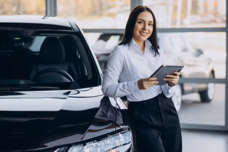 Vendedora sorridente segurando um tablet ao lado de um SUV preto em showroom